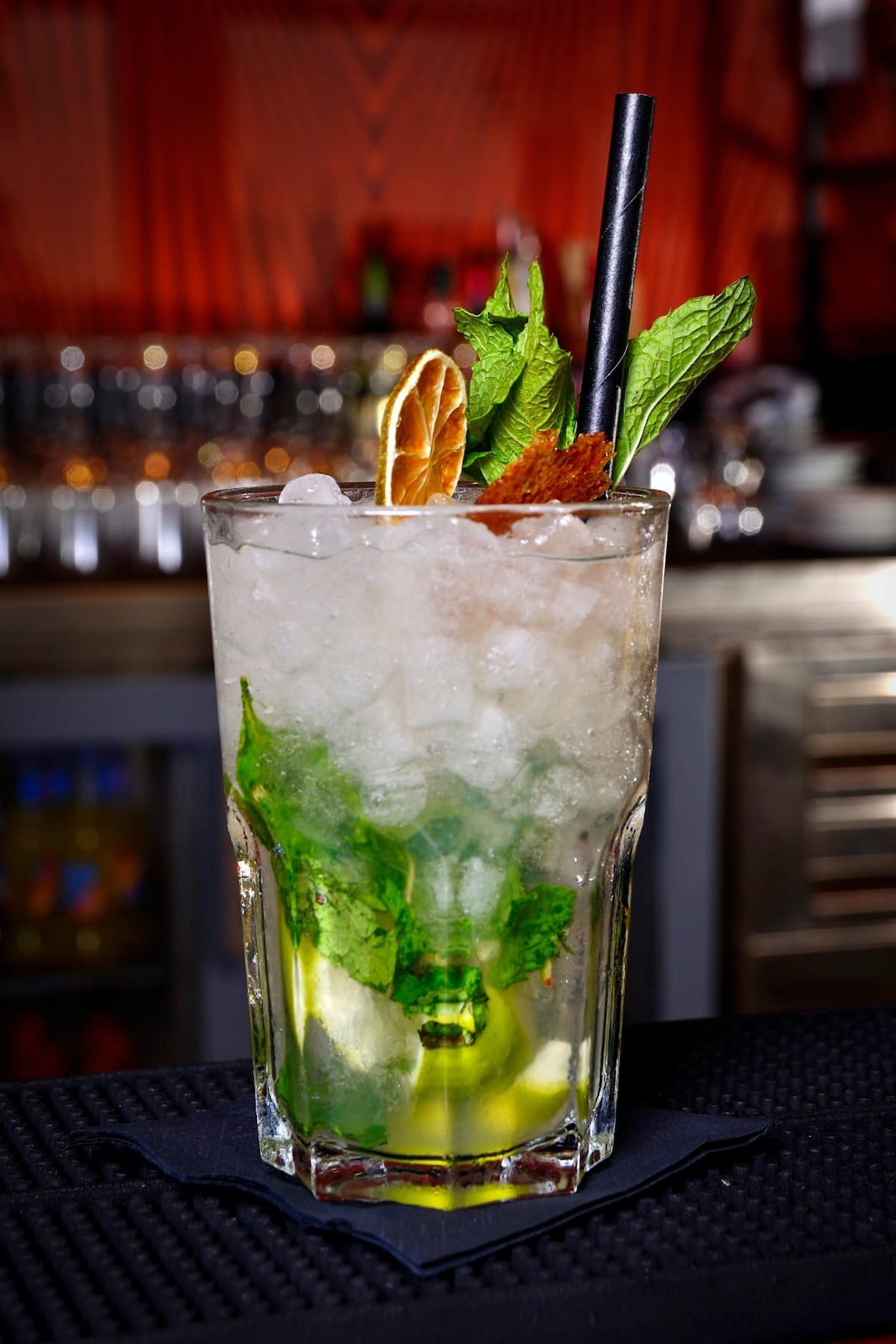 Close up of a mojito cocktail sitting atop a bar.