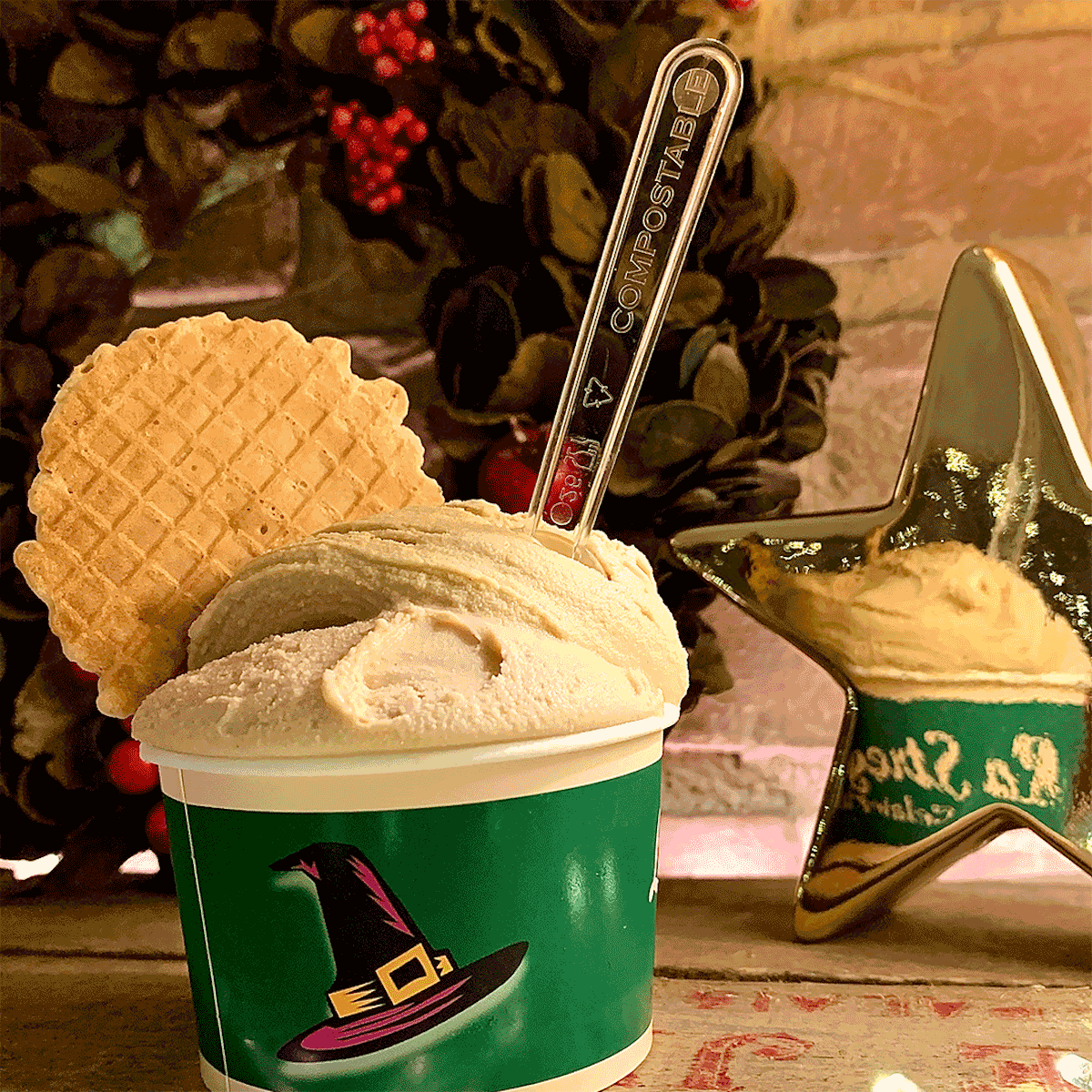 Gelato decorated with a thin cookie in a green cup with a witches' hat design.