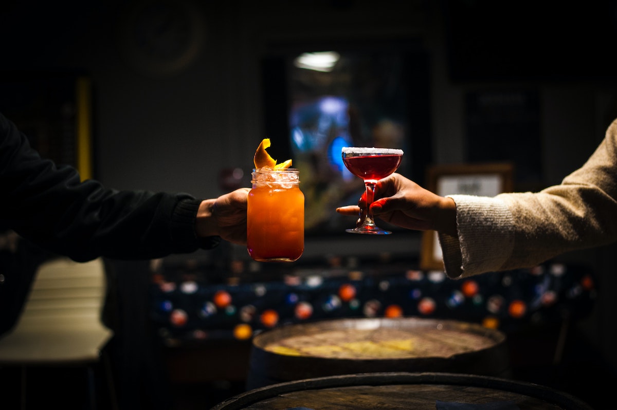 two people "cheers" with colorful cocktails