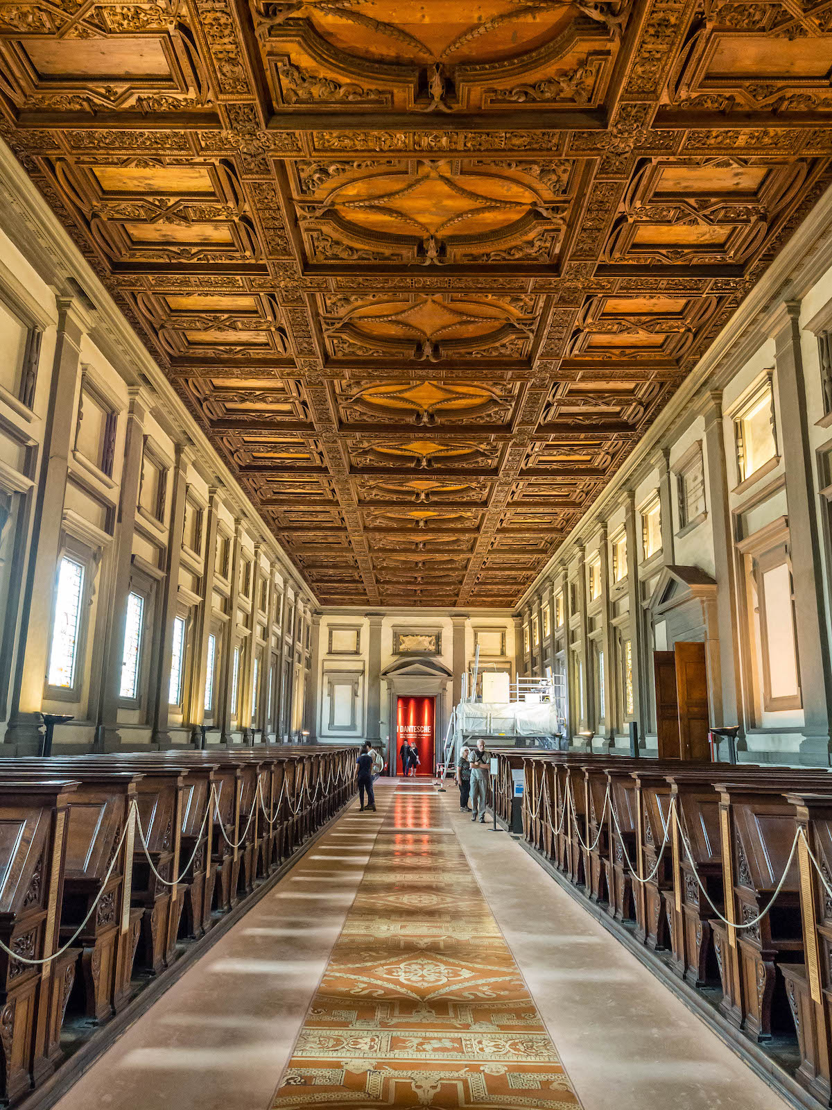 Long, high ceilinged room decorated in the Renaissance style and with a center aisle lined by rows of benches