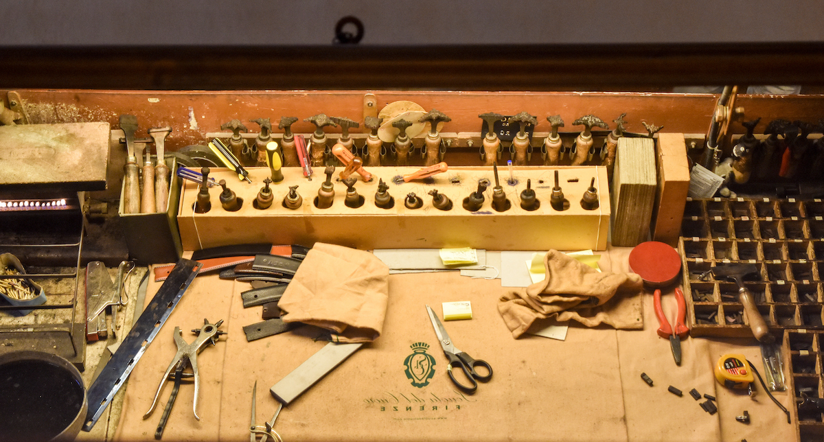 Traditional leatherworking tools on a work bench