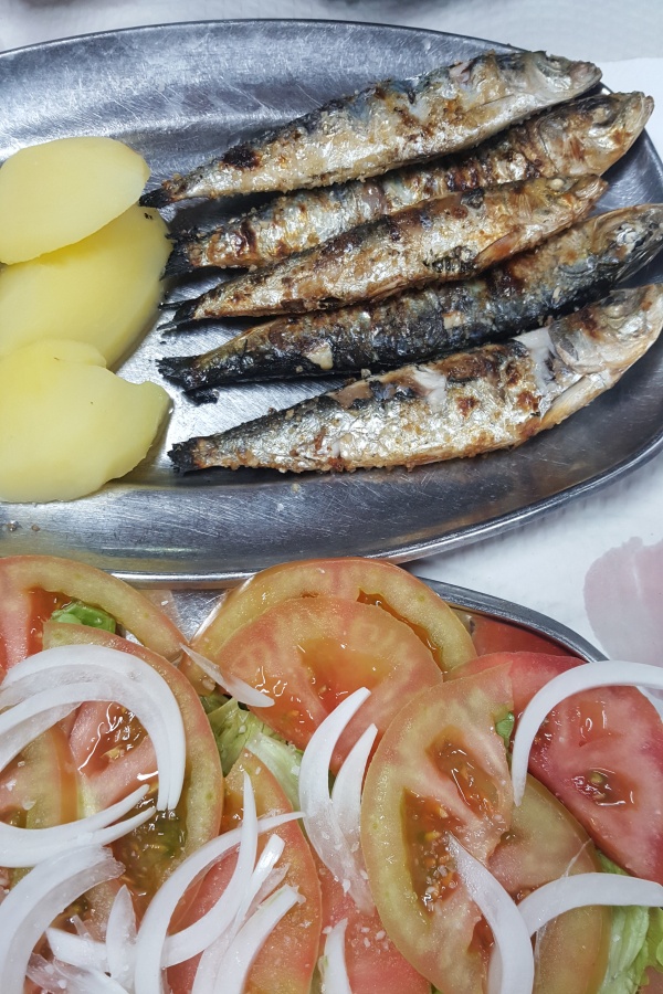 Stainless steel platters with grilled sardines and tomato salad