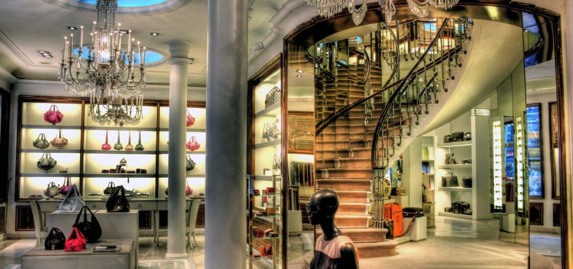 Interior of a luxury fashion boutique with chandeliers and a spiral staircase.