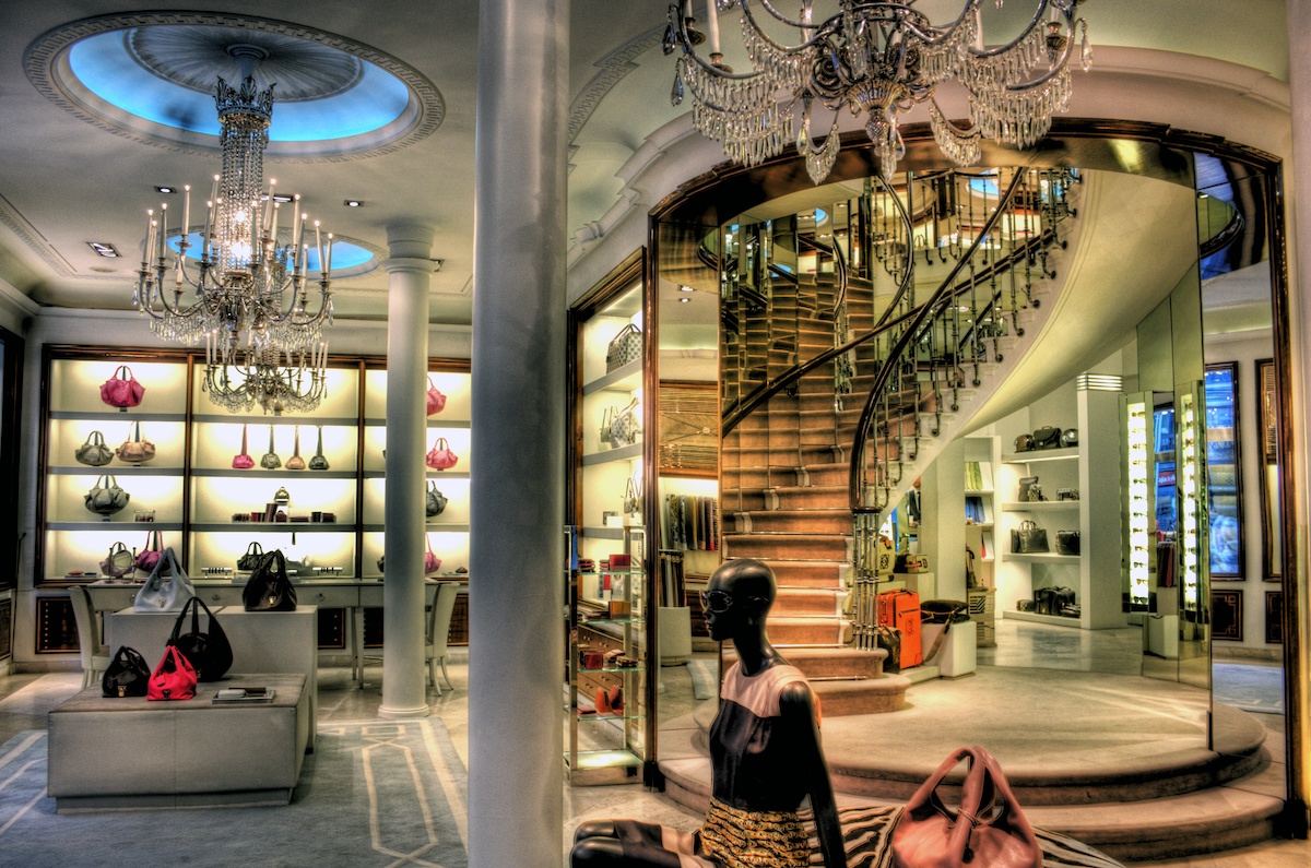 Interior of a luxury fashion boutique with chandeliers and a spiral staircase.
