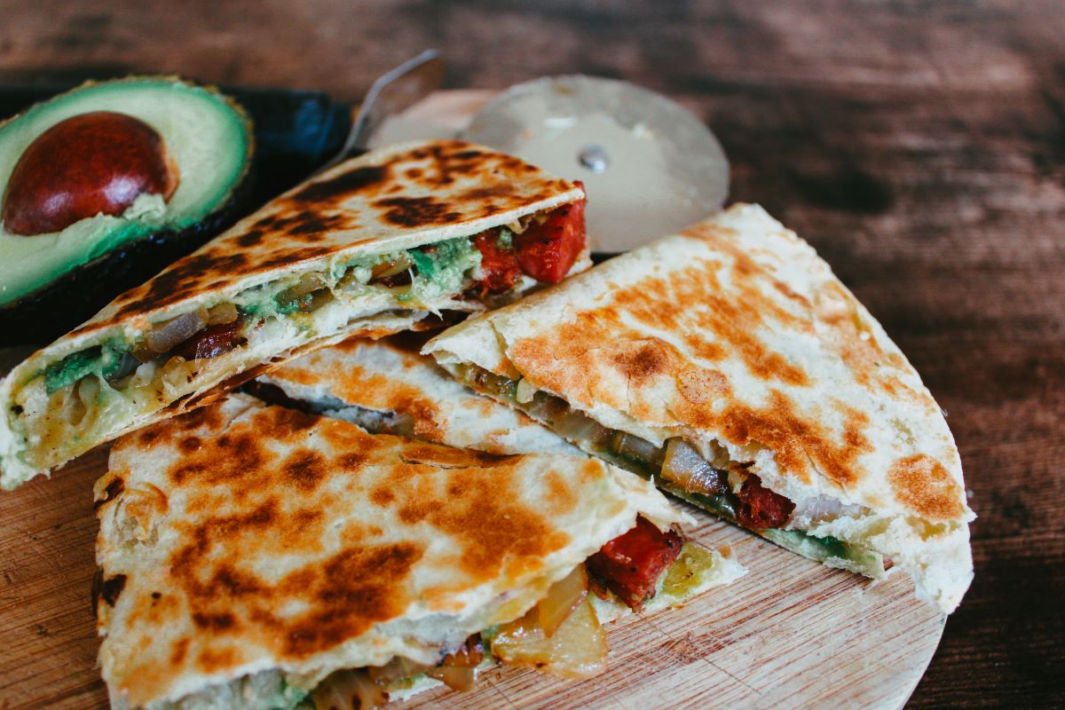 A plate of quesadillas with a side of avocado