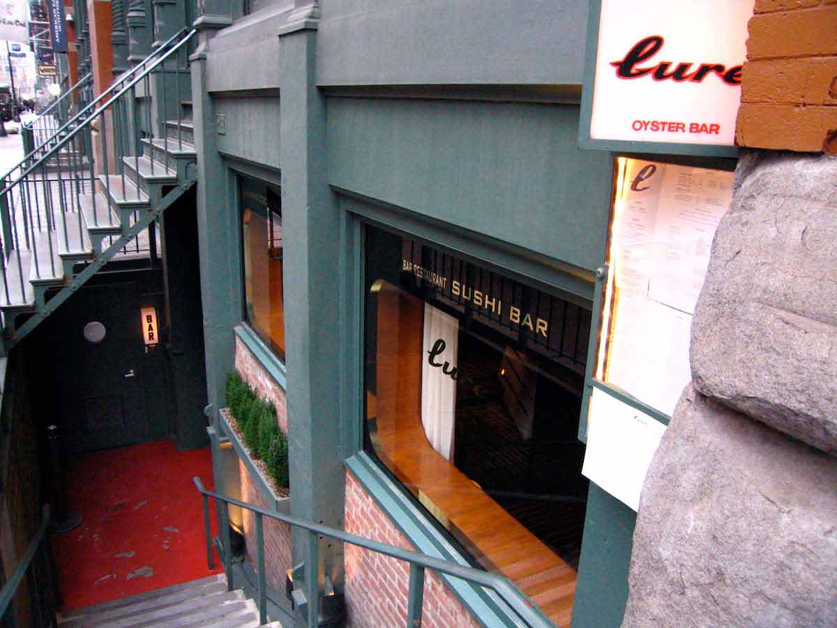Stairs leading down to a seafood restaurant with red brick and dark green paneling on the exterior.