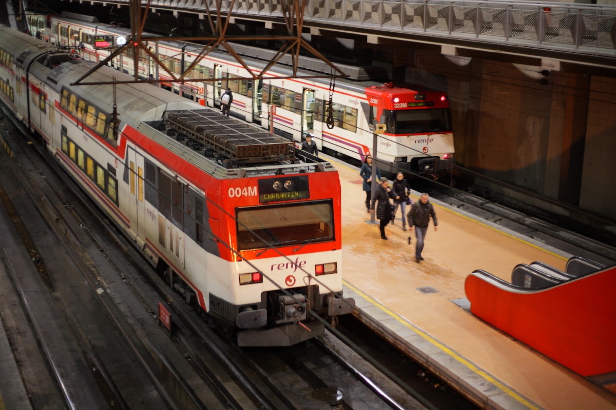 Red and white commuter trains at a station in Madrid.