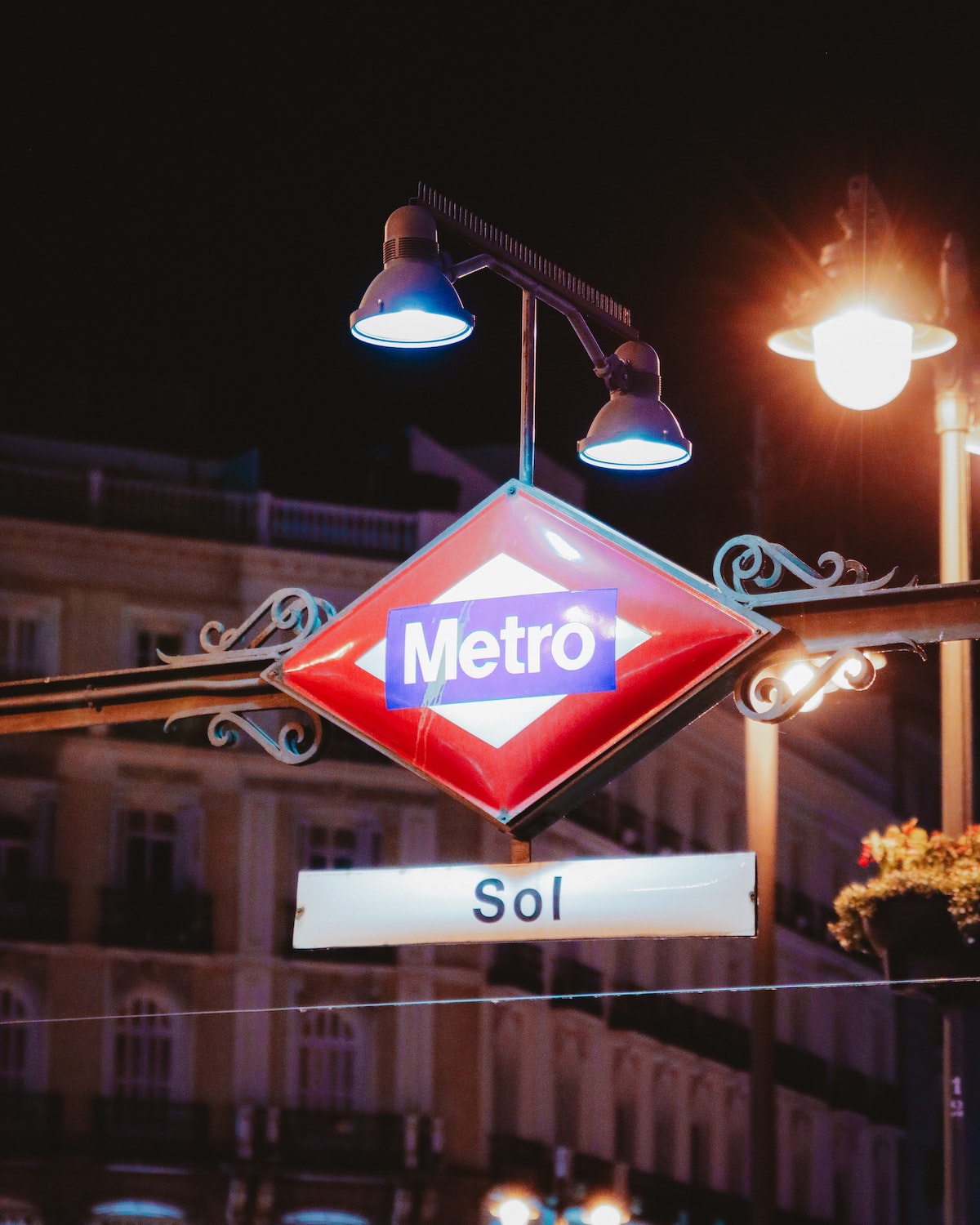 Red, white, and blue diamond-shaped sign marking the entrance to Madrid's Sol metro station at night