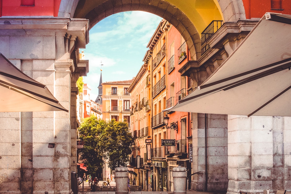 View through a stone archway of brightly colored buildings on a sunny day.