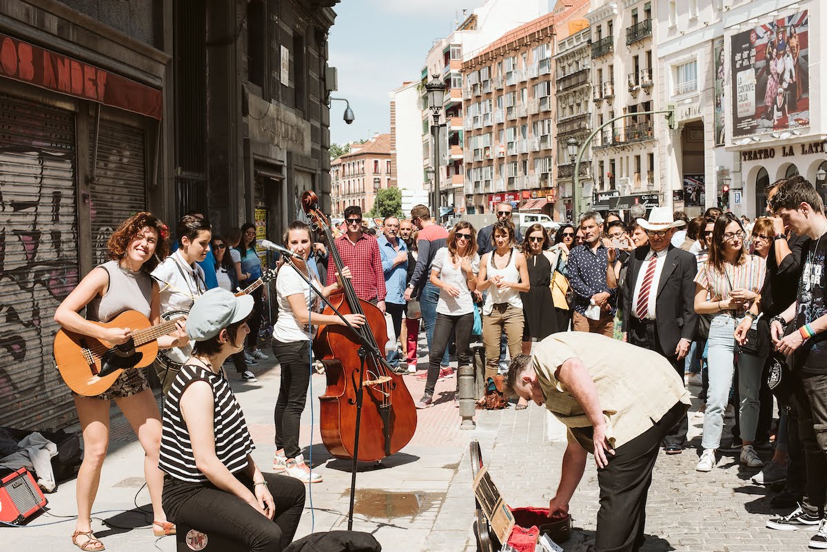 A crowd of people gathered around to watch a band of street performers play.