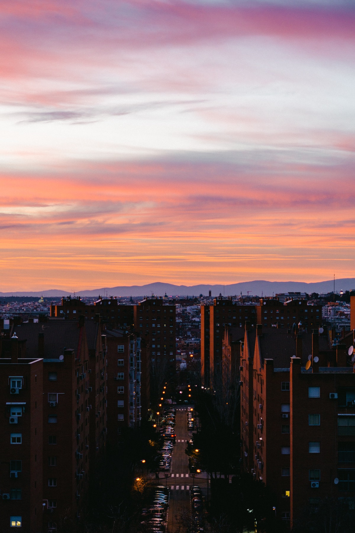 Sunset over a residential street in Madrid, Spain with mountains in the distance.
