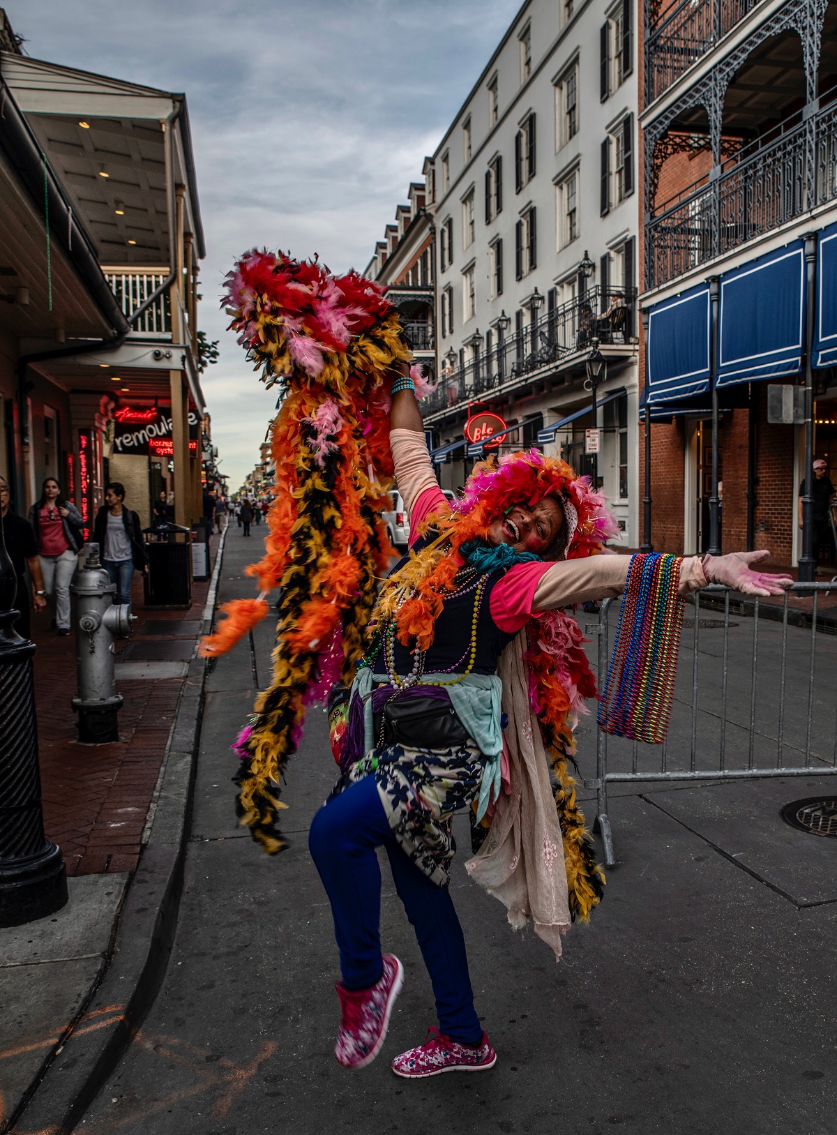 Woman standing in New Orleans street holds out armfuls of colorful plastic beaded necklaces