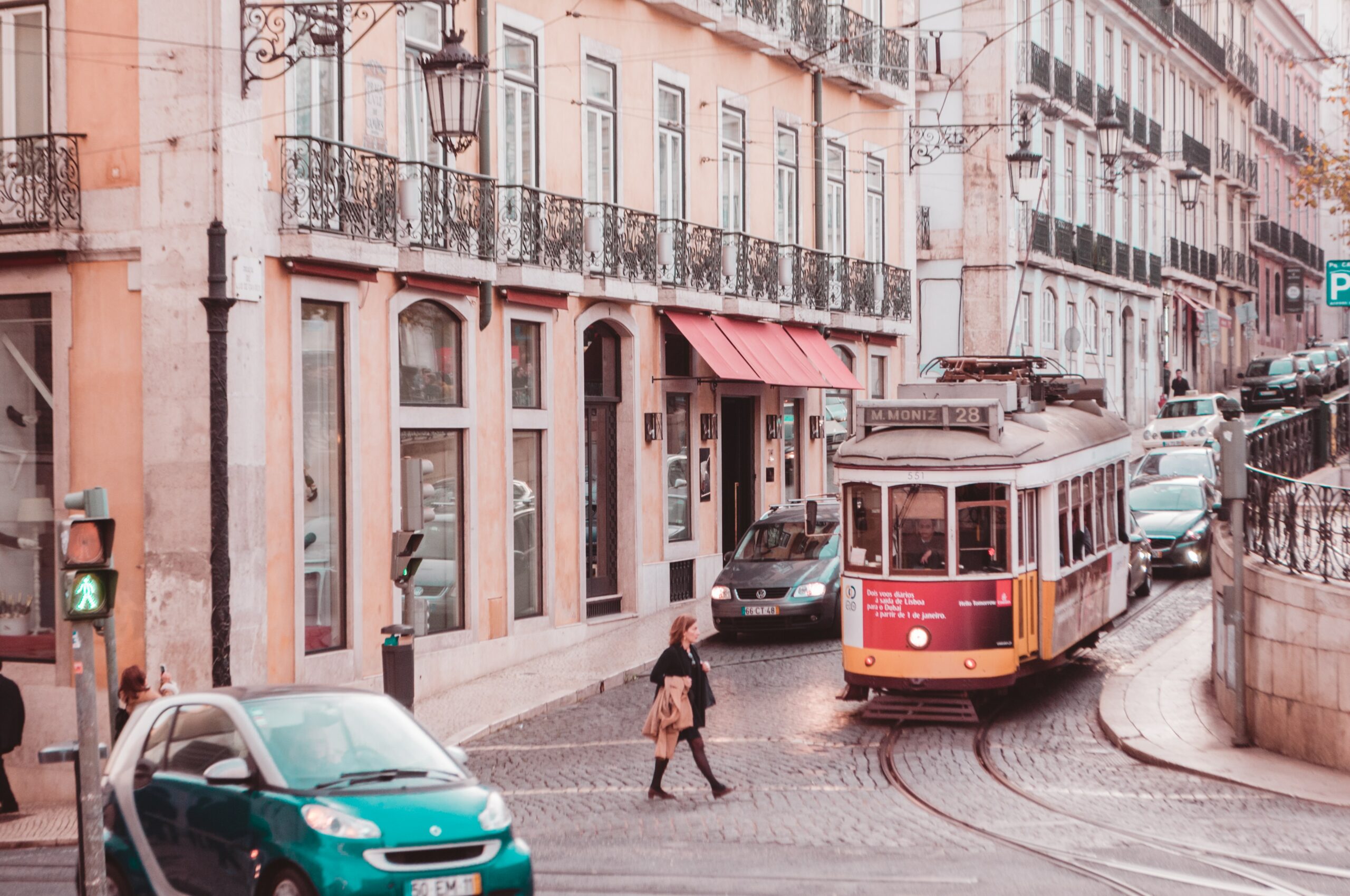 A tram and a lady walking in Lisbon