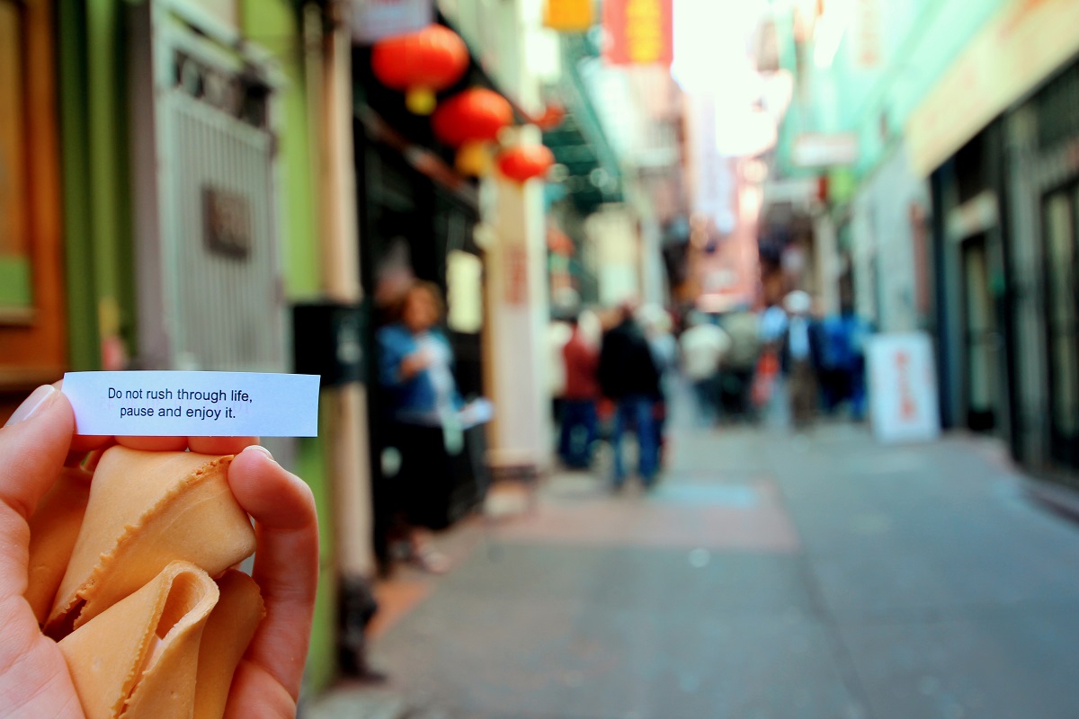 Hand holding fortune cookie and fortune on the street in San Francisco's Chinatown
