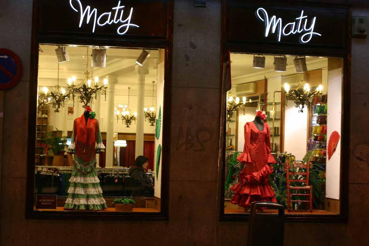 Flamenco dresses in a brightly lit shop window.