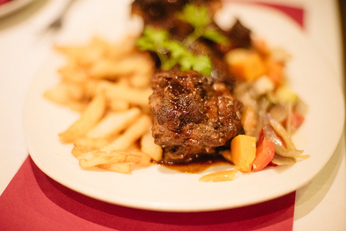 Dish of meat, french fries, and sauteed vegetables