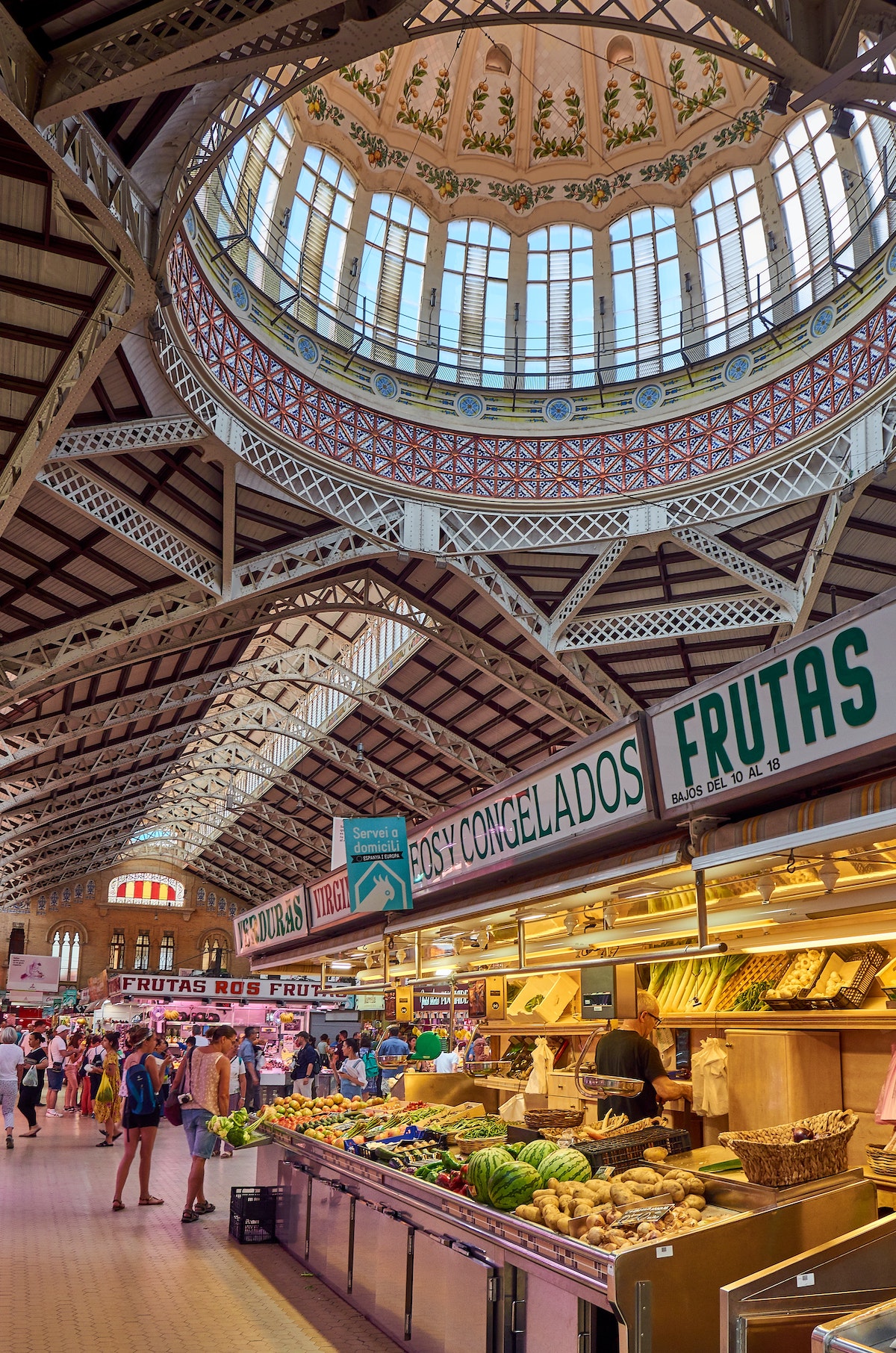 Interior of a large market hall with a glass dome above the stalls.