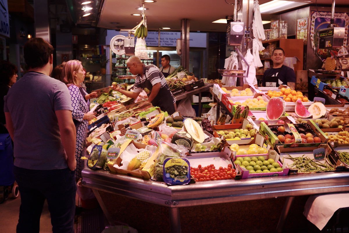 People shopping at a fresh produce stand inside a market