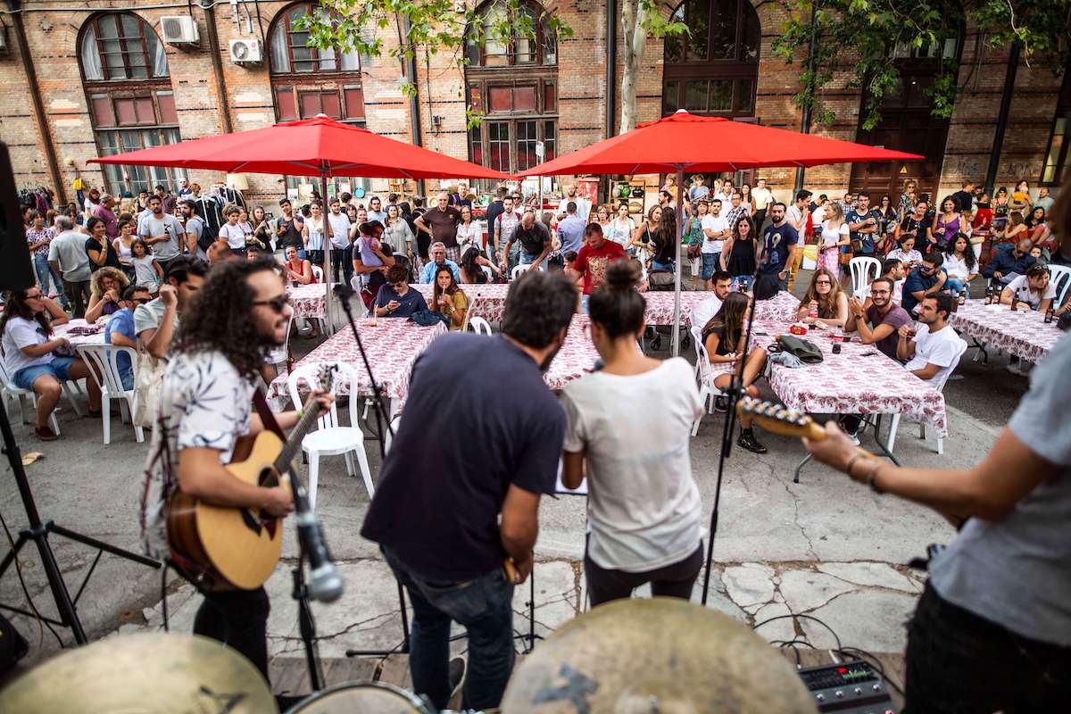 People seated at tables watching a concert performed by musicians on stage.