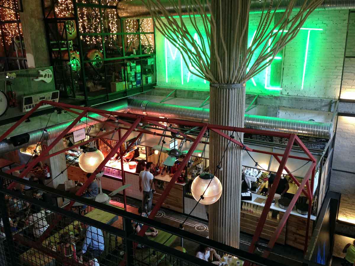 View from the second floor of a gastronomic market with neon lighting and modern decor.
