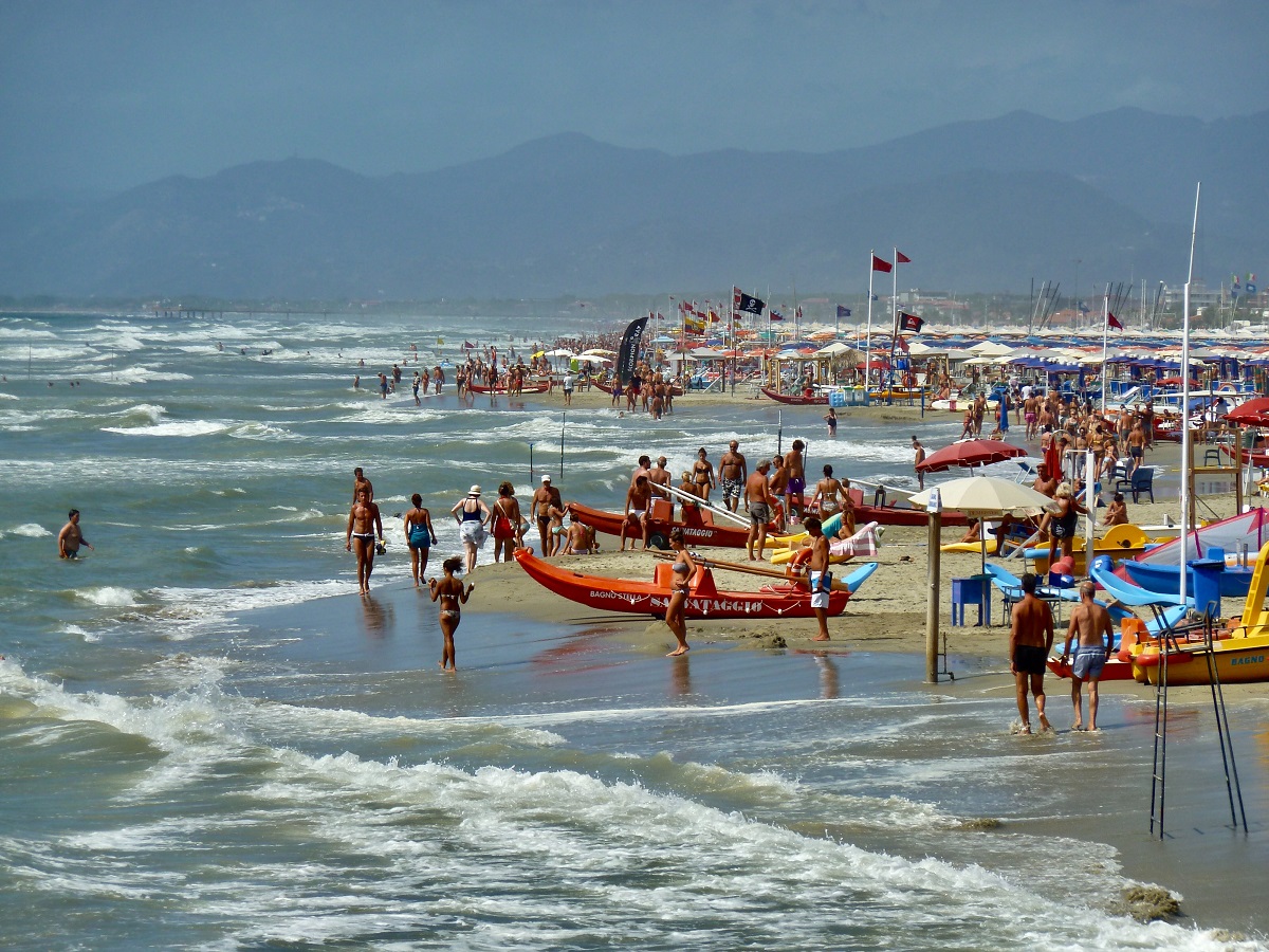 People and small boats on a sandy beach in Italy