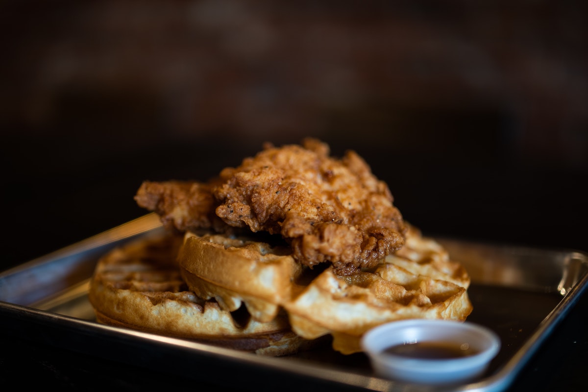 close up of a tray of fried chicken atop belgian waffles