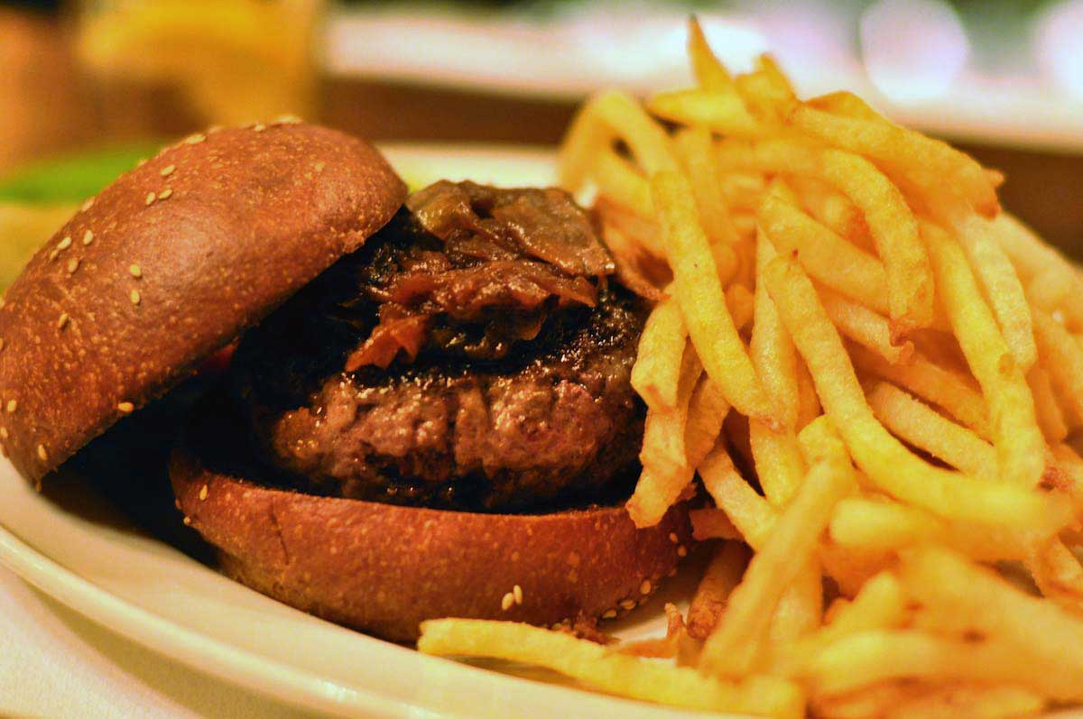 Burger next to a large pile of french fries