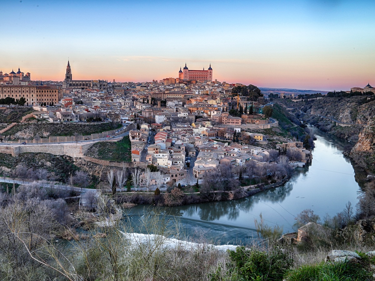 Panoramic view of Toledo, Spain at sunset taken from across a river.
