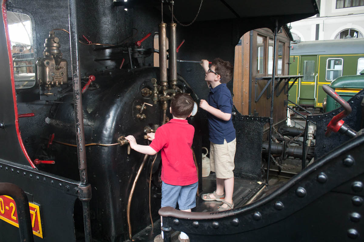 Two young boys exploring an old black train car