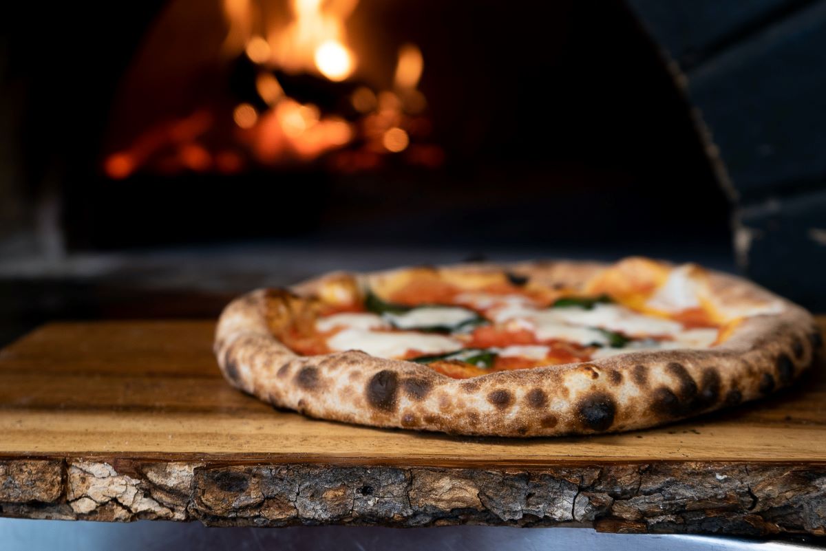 pizza on wooden shelve and stone fire over