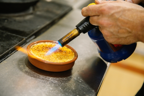 Caramelizing the top of a crème brûlée with a blowtorch