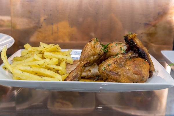 Grilled chicken pieces with French fries on a white plate. Knowing what you're getting is part of the process of ordering in Portugal. 