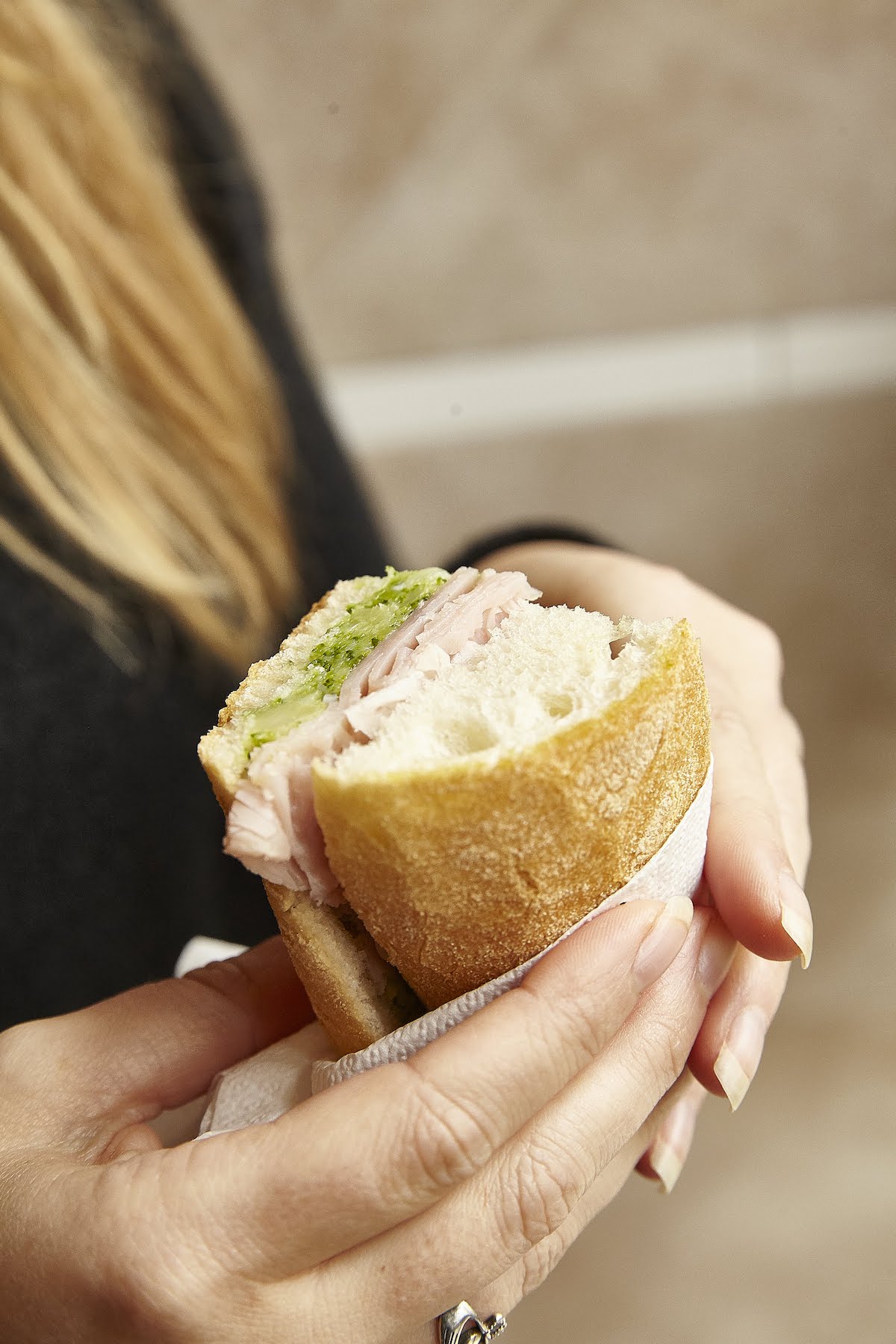 Close up of a person holding a small sandwich with prosciutto and broccoli