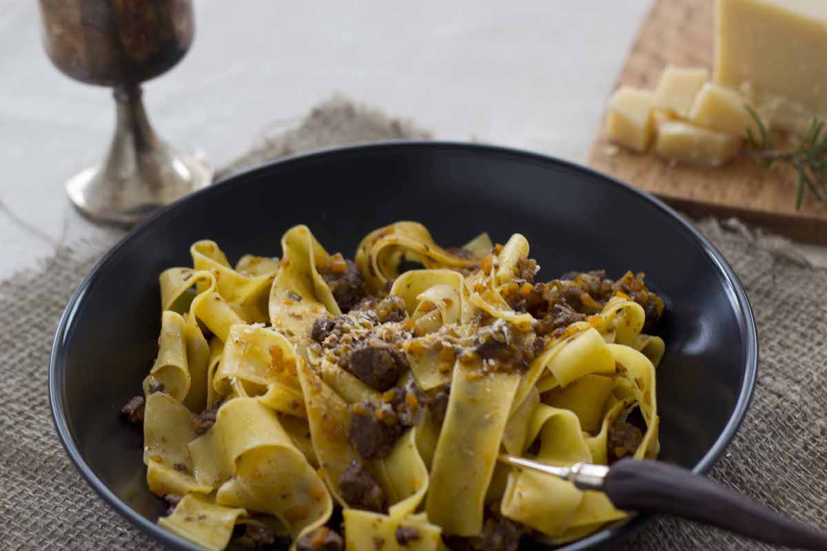 Wide pasta noodles with wild boar ragu on a black plate