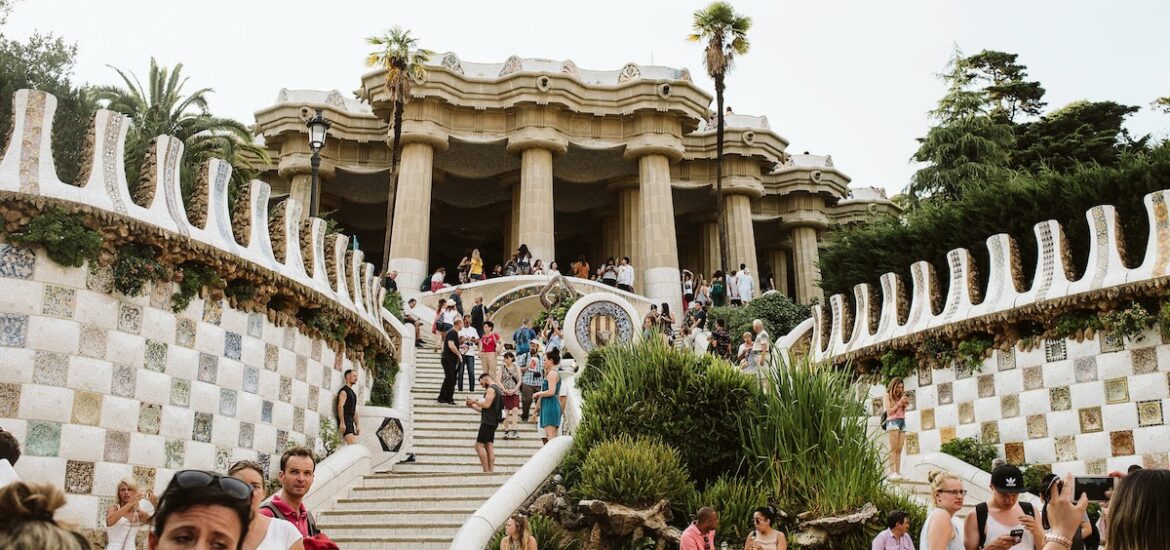 Groups of tourists near an outdoor staircase leading up to a whimsical modernist building with pillars