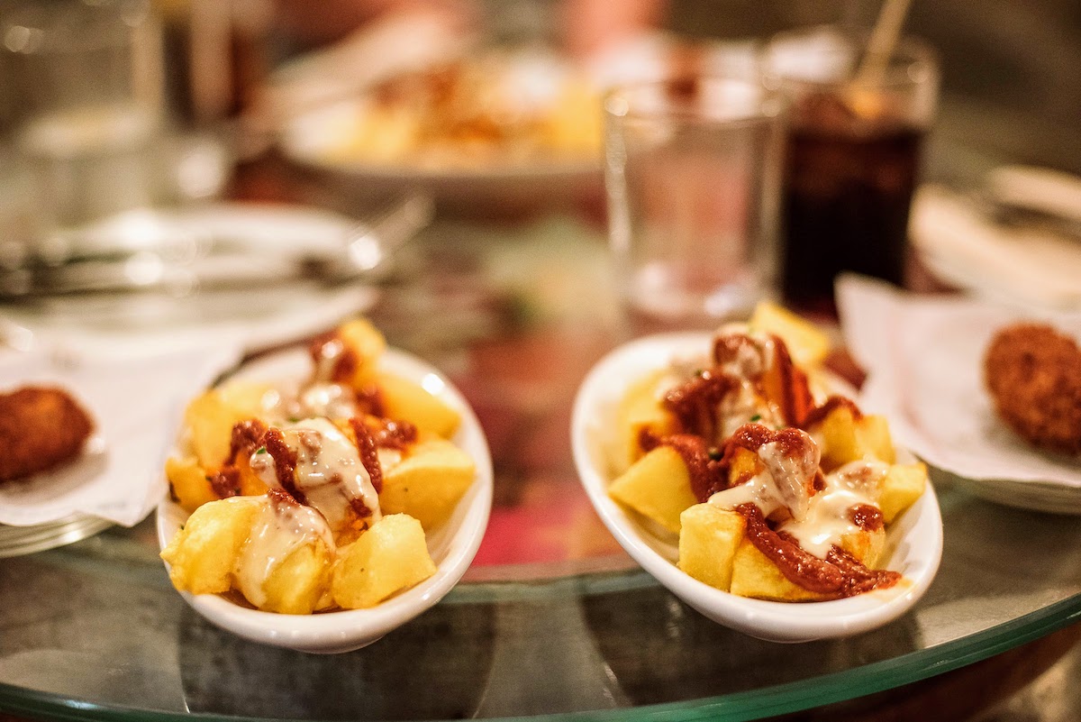 Two dishes of fried potatoes with spicy sauce and garlic mayonnaise.