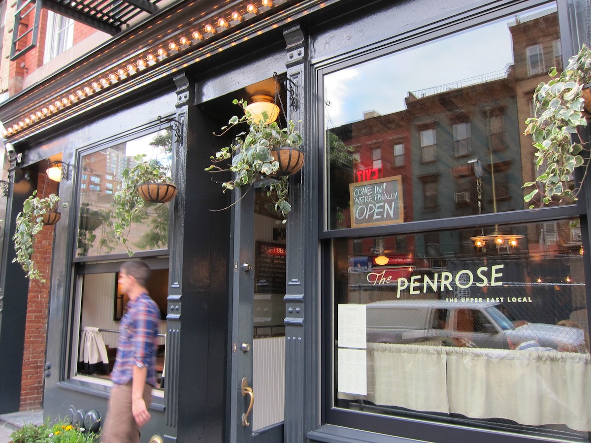 Exterior of The Penrose restaurant on NYC's Upper East Side, with large glass windows
