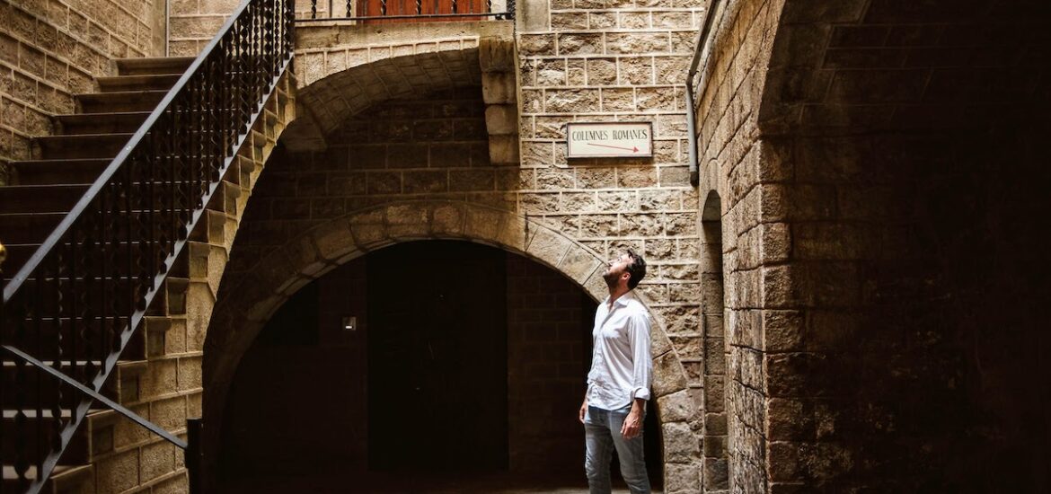 A man standing in a small inner courtyard of a historic stone building