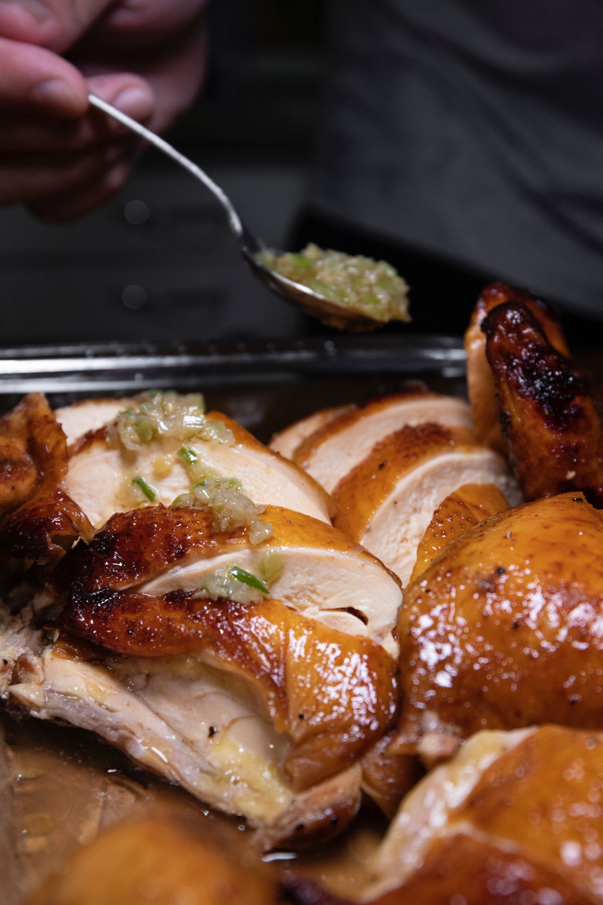 person serving green sauce on top of roasted chicken