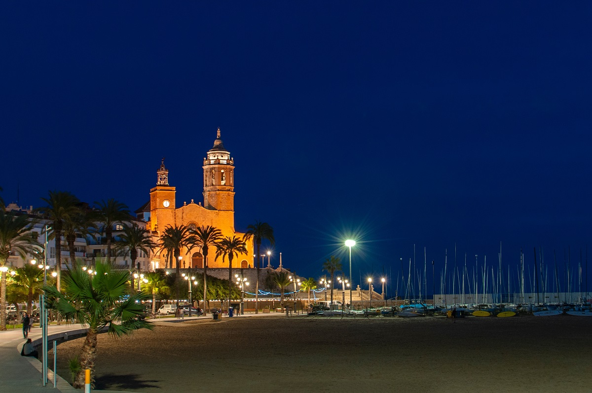 View of the Sitges port at night with street lamps lighting up the sand and the sea