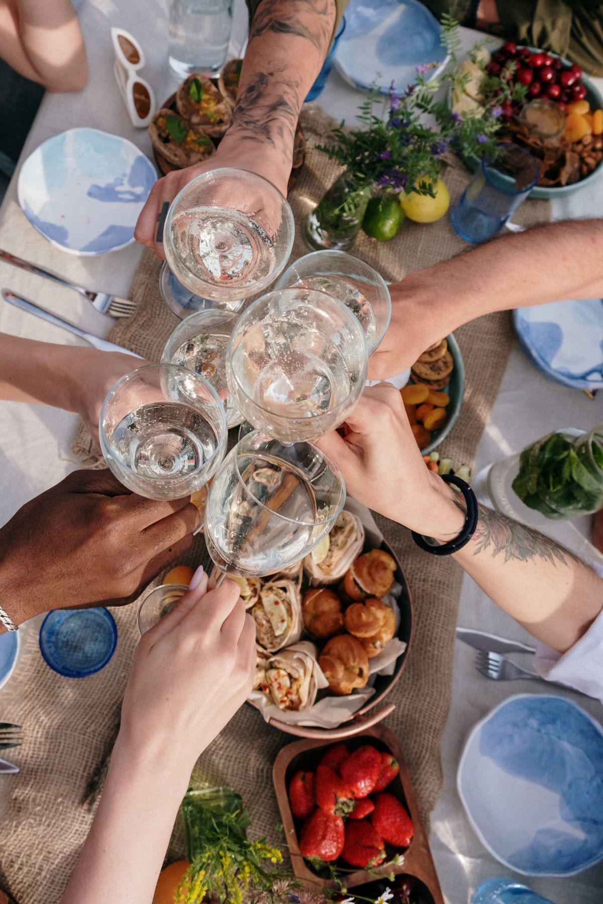 People cheering with clear glasses over table with food