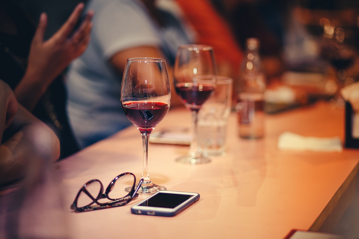 Glasses of wine on restaurant table with glasses and cell phone
