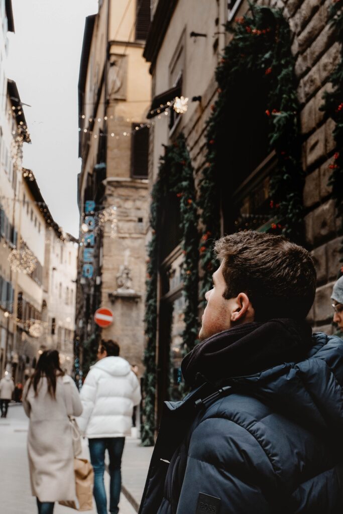 A man walks through the streets of Florence in the winter, with Christmas decorations on the shops