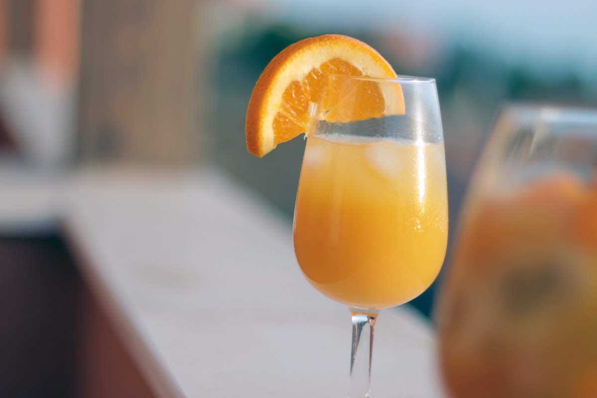 close up of a wine glass filled with mimosa and an orange slice garnish