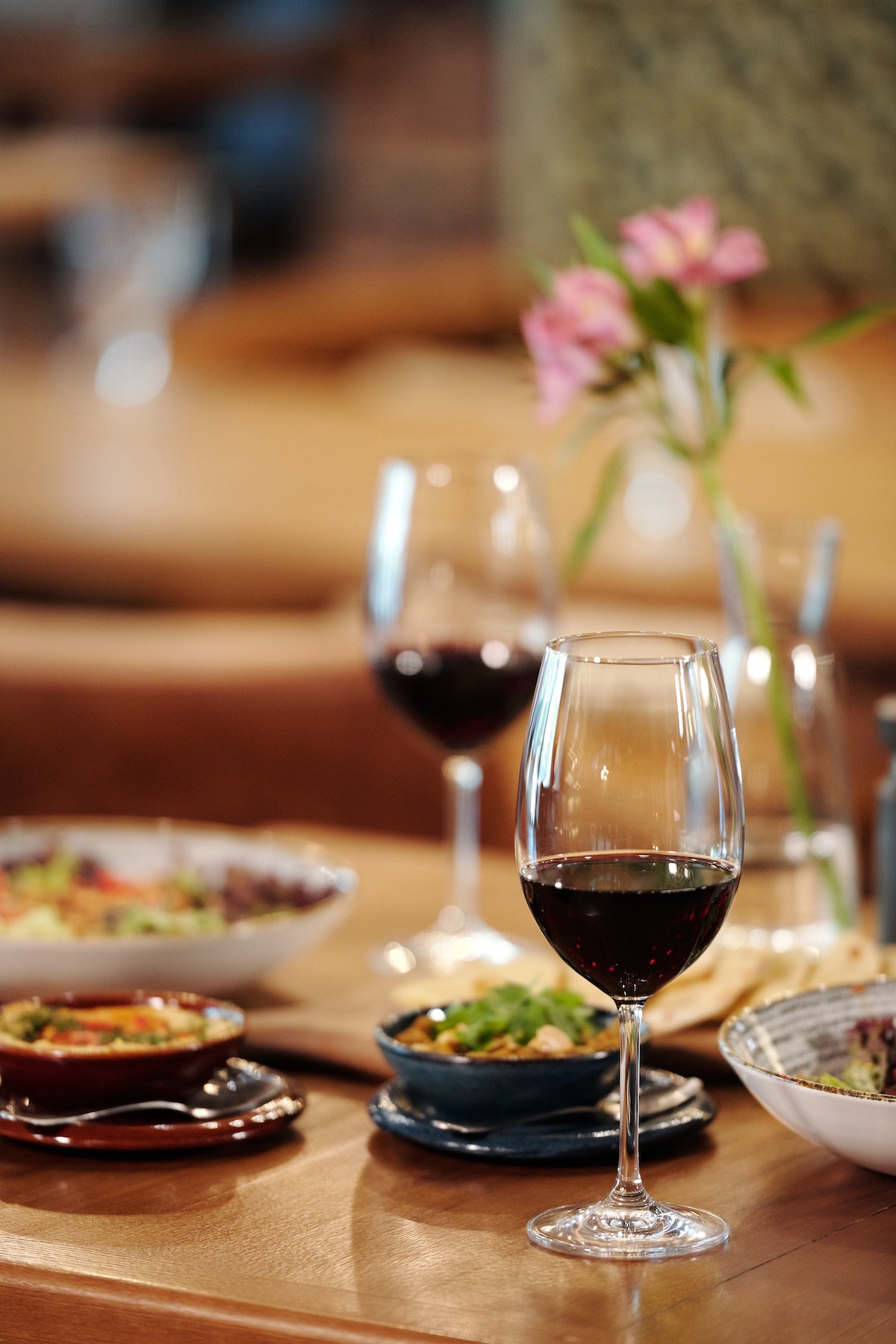 two glasses of red wine and small plate dishes on a wooden table
