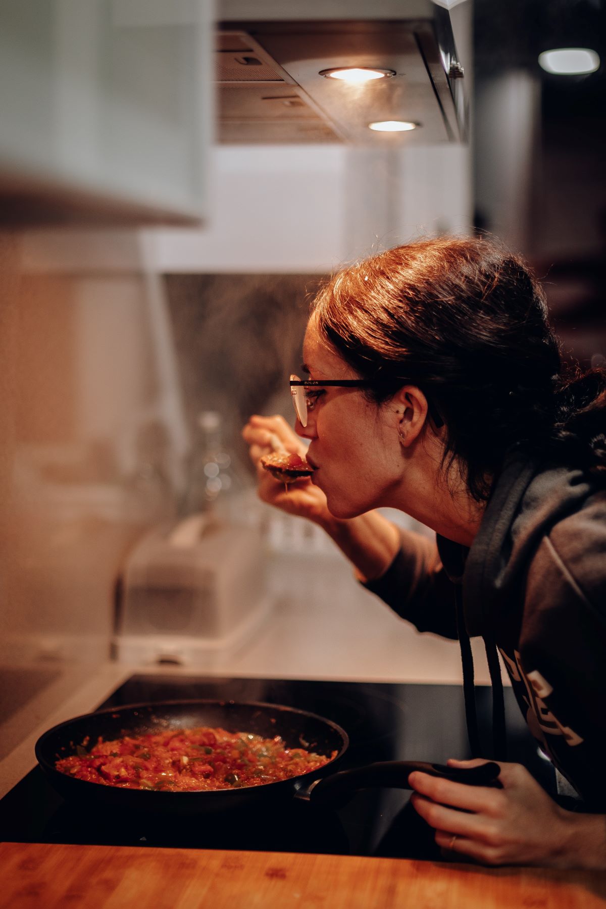 woman tasting food over oven