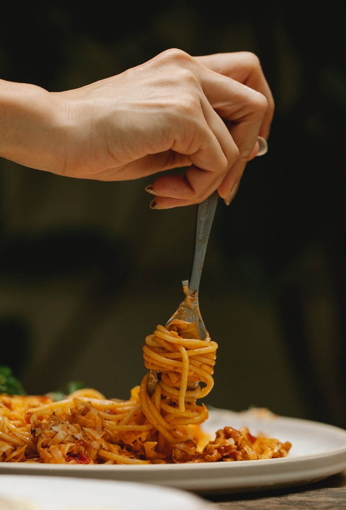 A woman twirls spaghetti noodles onto her fork