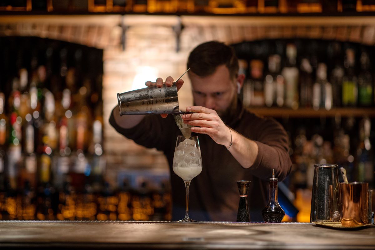 bartender pouring cocktail behind the bar