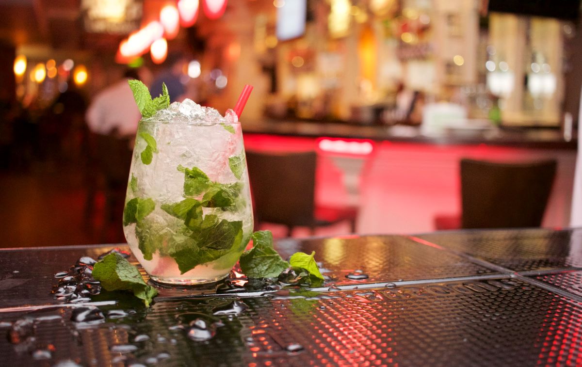 white cocktail with mint in bar with neon lights