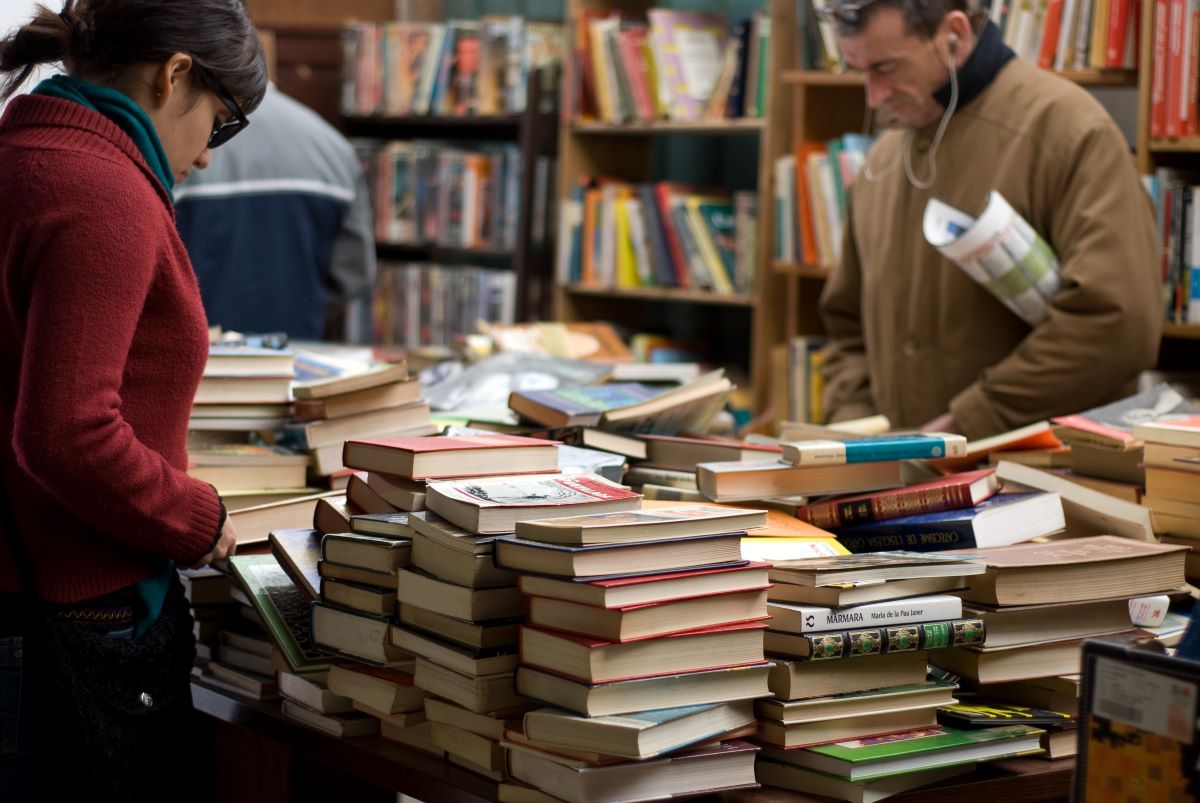 Woman-and-Man-Standing-Beside-Piles-of-Books-in-bookstore